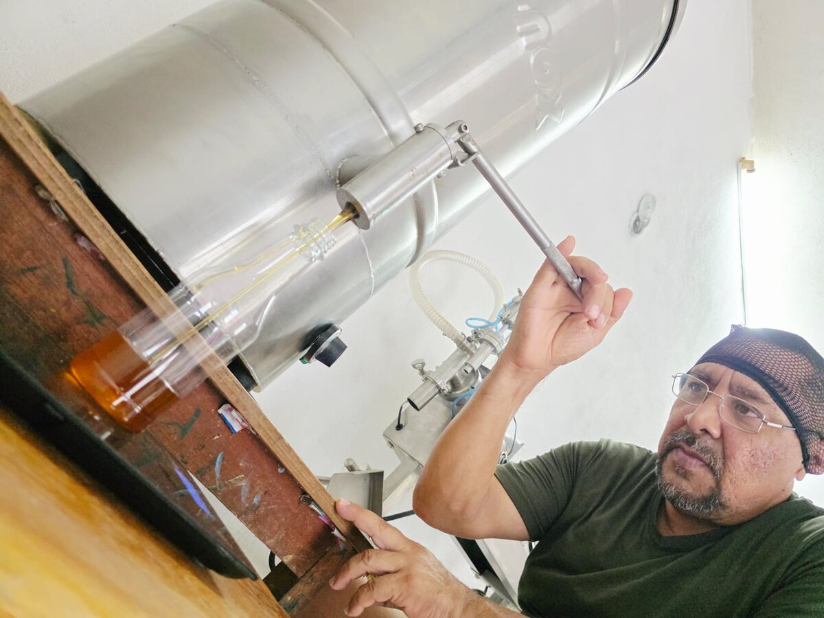 Eulogio llena una botella de miel desde un tanque de acero