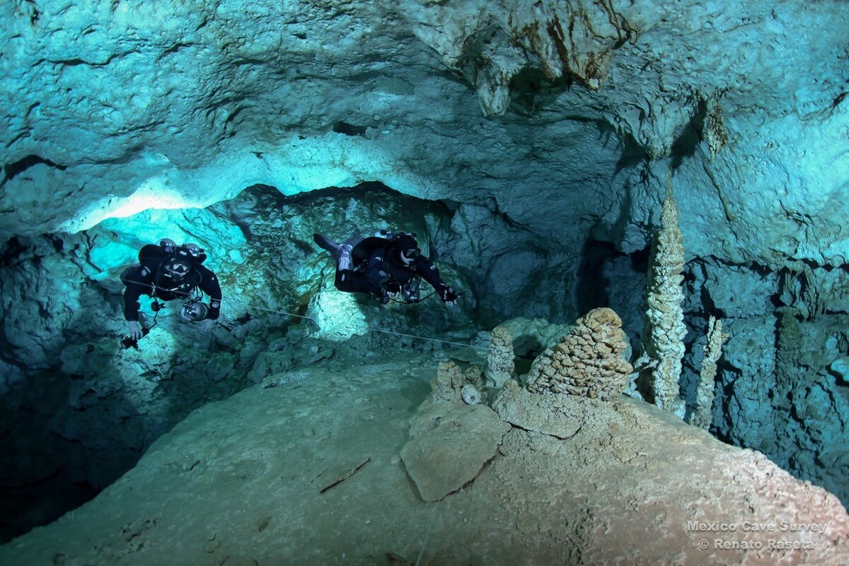 Dos espeleobuzos exploran un cenote inundado con formaciones de roca caliza
